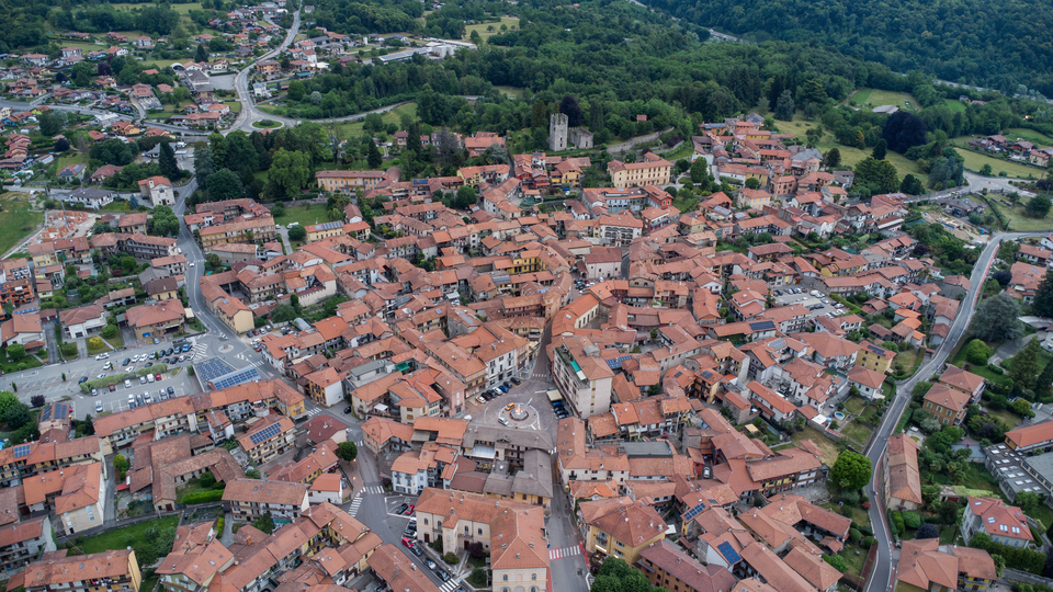 Veduta aerea del centro storico di Invorio Inferiore, con Piazza Martiri e la fontana restaurata in primo piano e la torre viscontea sullo sfondo.