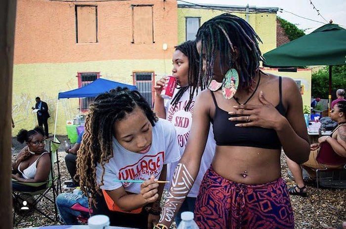 Guests at Pentridge Station beer garden enjoy a warm evening; one guest paints onto the arm of another.