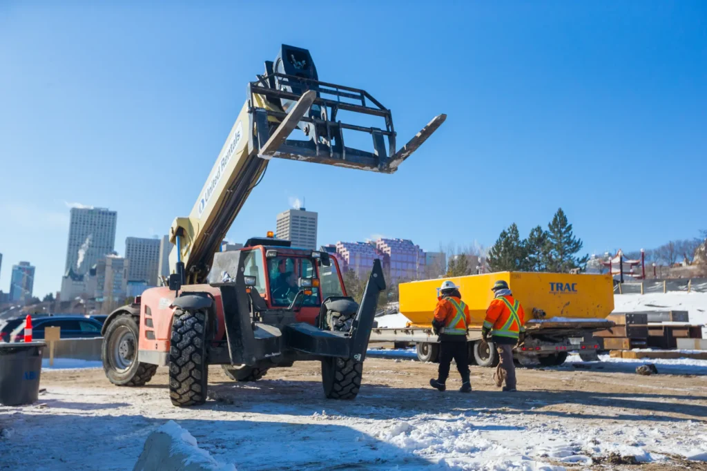 heavy equipment being used by craft workers at a snowy jobsite.