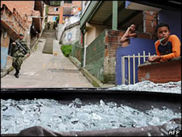 Soldado colombiano pasa por un auto destruido por las balas en el barrio de Santo Domingo Savio en Medellín.