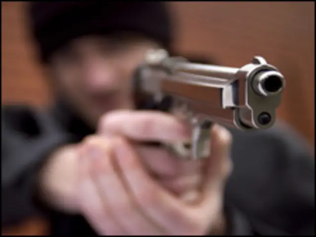 Joven apunta con una pistola.