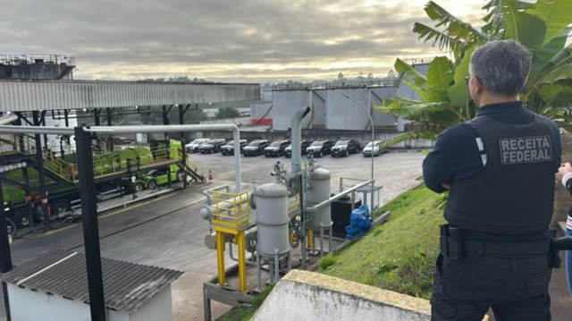 Agente da polícia federal observa do alto de um barraco refinaria de combustível