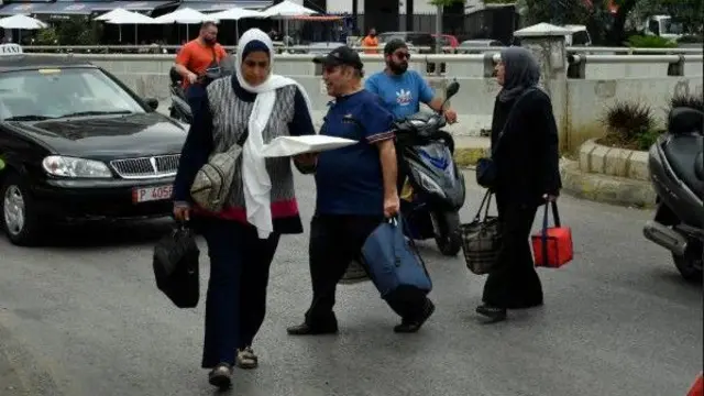 أشخاص يحملون متعلقاتهم بينما يغادرون ضواحٍ في جنوب بيروت