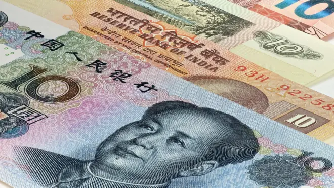Hình ảnh tiền giấy từ nhiều quốc gia khác nhau, bao gồm Ấn Độ và Trung Quốc, với một tờ tiền nhân dân tệ của Trung Quốc có hình cựu lãnh đạo Mao Trạch Đông ở phía trước