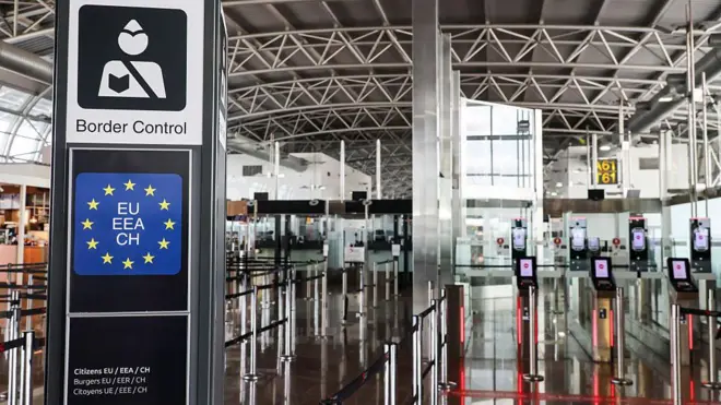 Border control, sınır kontrolü yazılı bir geçişin ardından pasaport kontrol alanı ve otomatik geçişler görünüyor. 