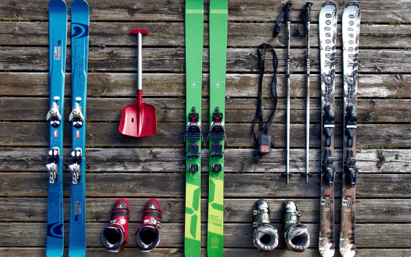 4K Ultra HD PC desktop wallpaper showing skis, poles, boots and a shovel arranged on weathered wooden planks — colorful ski gear for skiing and winter sports.